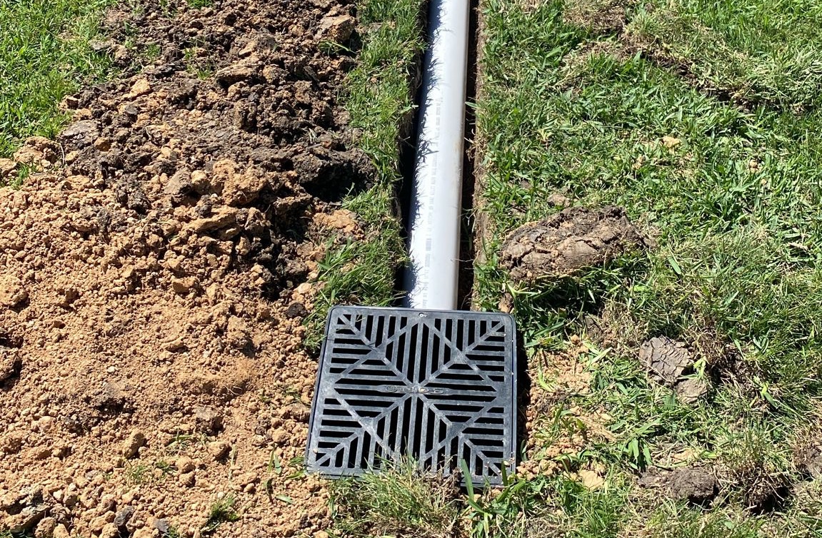 Catch basin grate connected to schedule 40 PVC drainage pipe during installation in Houston