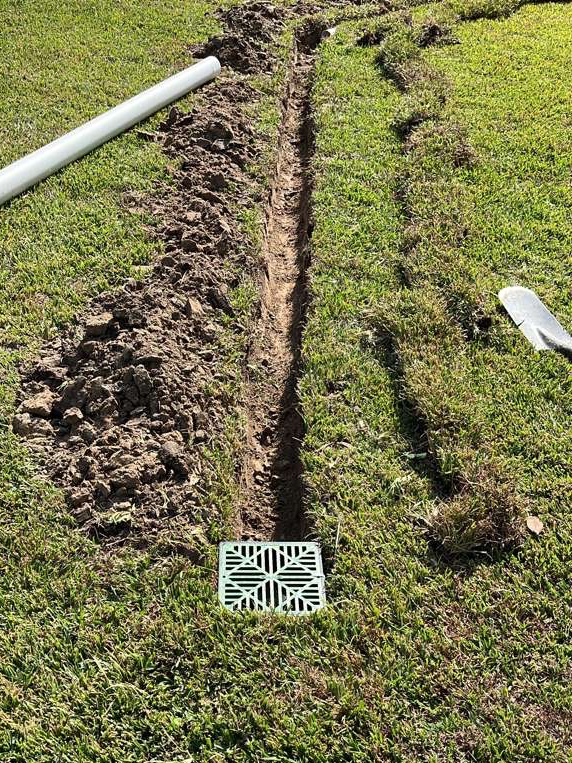 Catch basin and PVC pipe trench during professional drainage installation in Houston