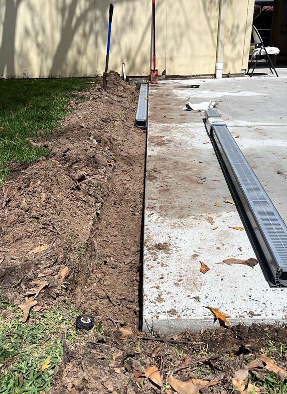 Channel drain being installed along concrete edge in a Houston property