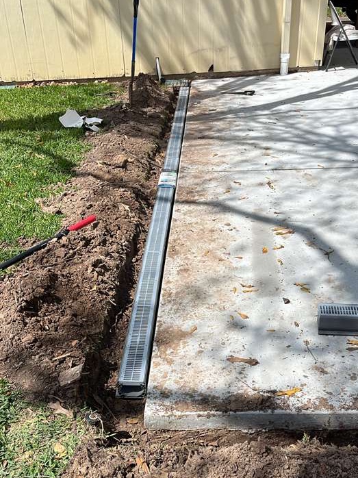Channel drain being installed along a driveway edge in Houston