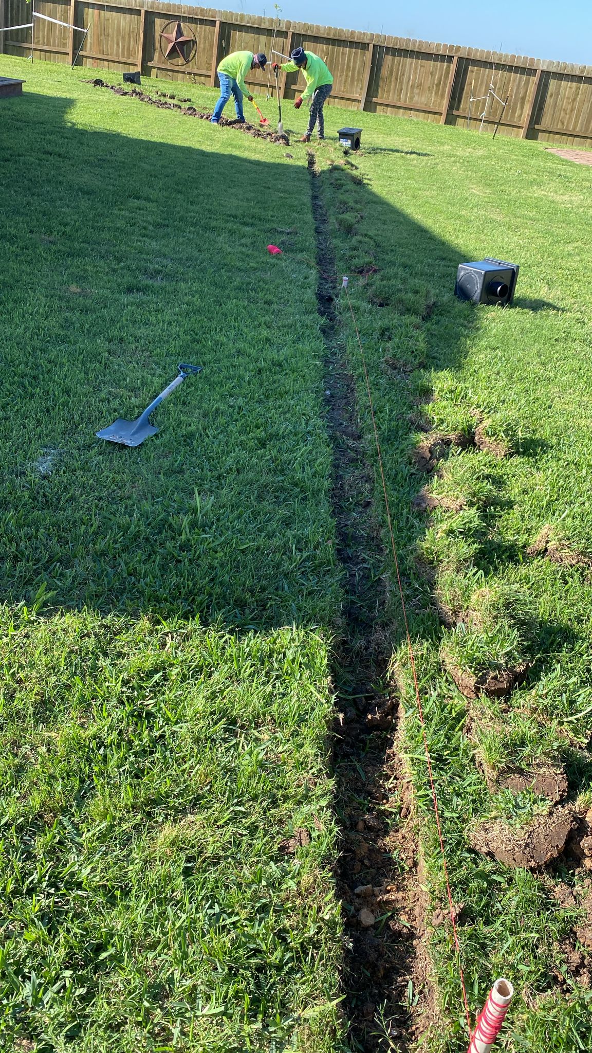 713 French Drains crew trenching a long French drain line across a Houston backyard