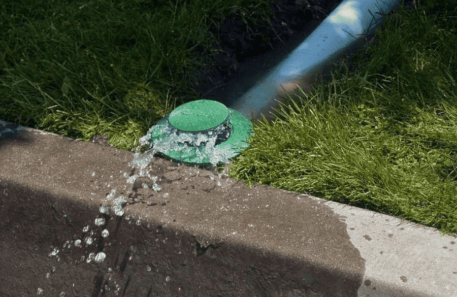 Pop-up drain emitter installed in a green lawn for drainage in Houston TX